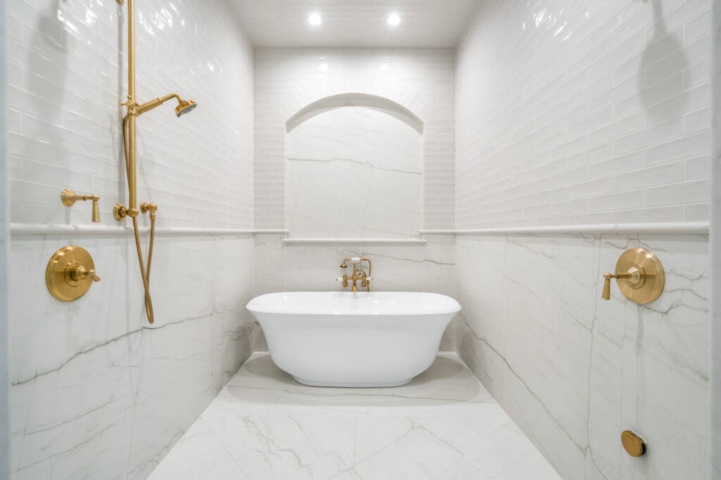 Bathroom remodel showing white bathtub and gold harware