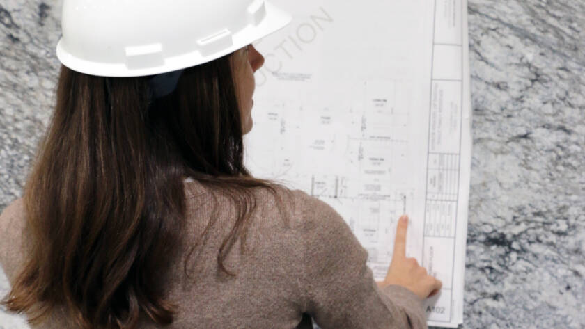 A woman looking at schematics amongst a natural stone slab selection in stone studio in naperville, il