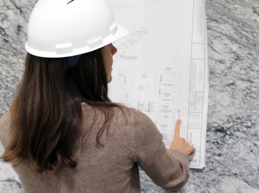 A woman looking at schematics amongst a natural stone slab selection in stone studio in naperville, il